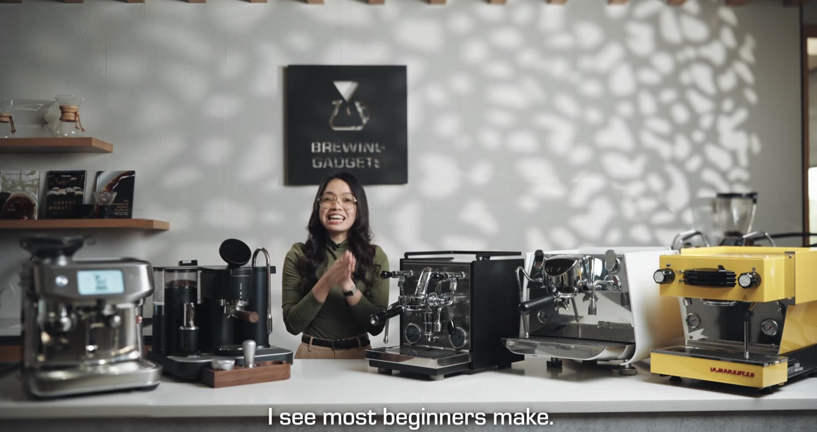 Brewing Gadgets host in front of a counter with five espresso machines of different models.